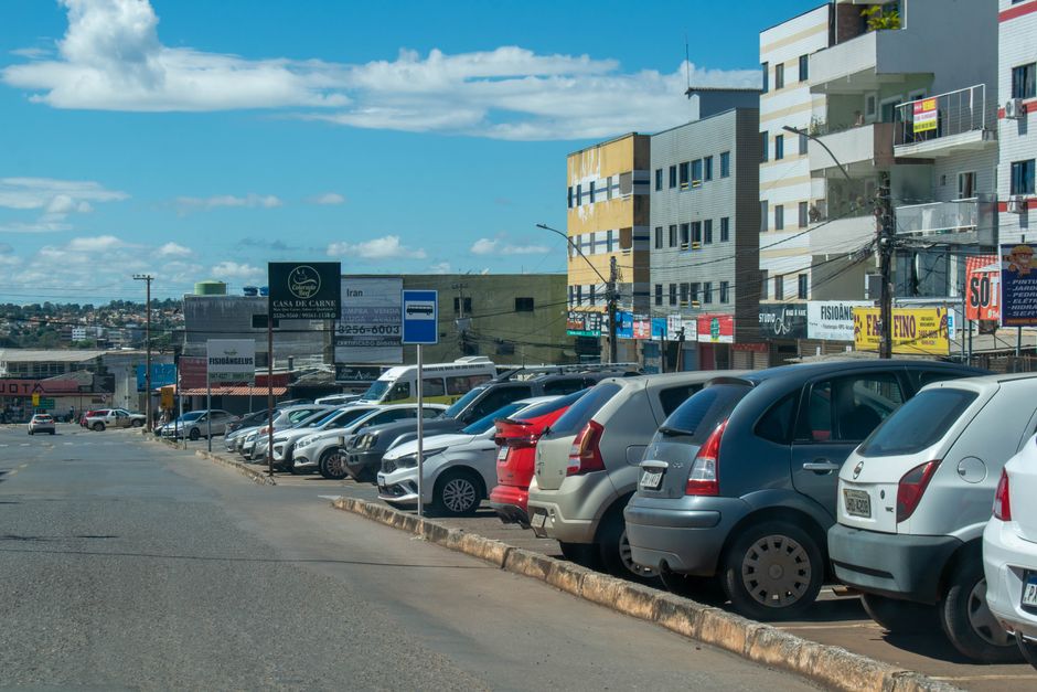 Infraestrutura Brasília. — Street view in Brasilia with lined parked cars and vibrant urban buildings under a bright sky.